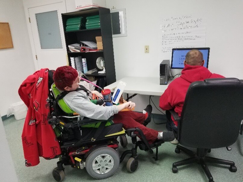 Image of disabled person and helper working on a computer